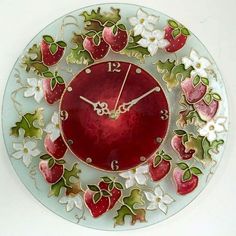 a red clock with white flowers and strawberries on the face is hanging from a wall