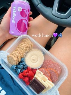 a person is holding a can of soda and some food in their lap while driving