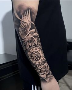 a man's arm with a clock and roses tattoo design on the left arm