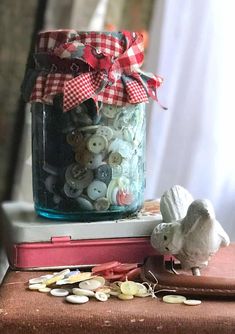 a jar filled with lots of buttons sitting on top of a table next to a mouse