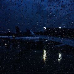 an airplane sitting on the tarmac at night with rain drops falling off it's windows