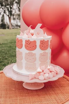 a hello kitty cake on a table with balloons in the background