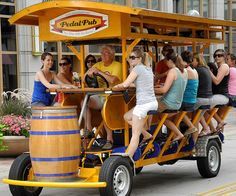 a group of people riding on the back of a yellow cart with barrels in it