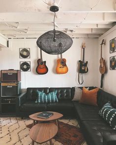 a living room with guitars hanging on the wall and a couch in front of it