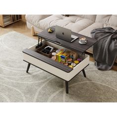 a coffee table with an open drawer underneath it on top of a rug in front of a couch