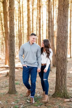 an engaged couple standing in the woods