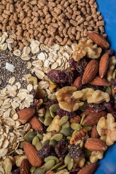 a blue bowl filled with granola, nuts and other food items on top of it