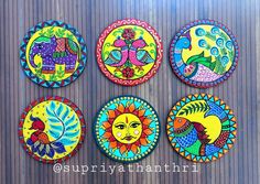 four colorful painted plates sitting on top of a wooden table