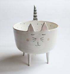 a white ceramic cat planter with a black horn