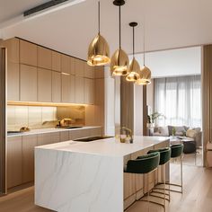 a modern kitchen with marble counter tops and gold pendant lights hanging from the ceiling over the island