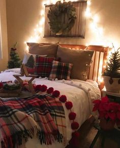 a bed covered in blankets and poinsettis with lights on the headboard