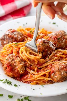 someone is eating spaghetti with meatballs and sauce