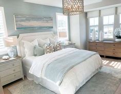 a bedroom with blue walls, white bedding and gray carpeted area rugs