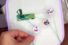 someone is stitching on the back of a cross - stitch project with buttons and yarn