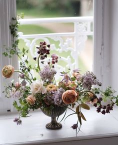 a vase filled with lots of flowers sitting on top of a window sill