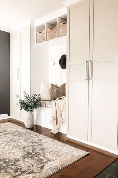 a living room with white cabinets and a rug on the floor in front of it