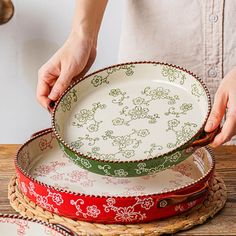 a woman is cutting up some plates on a wooden table with red and green trimmings