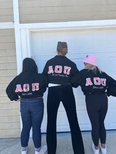 three girls in matching sweatshirts standing next to a garage door