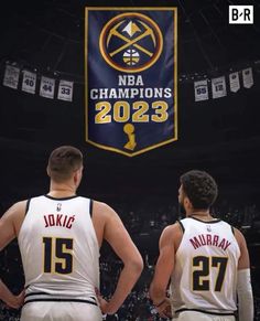 two basketball players are standing in front of a banner with the logo of the team