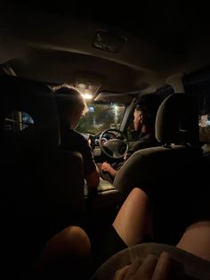 two people sitting in the passenger seat of a car at night