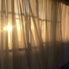 the sun is shining through sheer curtains