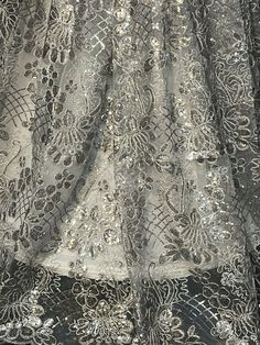 Good quality, sparkly, and unique embroidered silver grey floral lace with sequins. Width is 48”-50”. Sold by the yard. Elegant Silver Sequin Fabric With Floral Embroidery, Silver Embroidered Fabric With Floral Design, Silver Lace With Intricate Embroidery, Silver Embroidered Lace For Party, Festive Silver Sequined Embroidered Fabric, Silver Embroidered Fabric With Sequins For Festive Occasions, Festive Silver Embroidered Fabric With Sequins, Festive Silver Lace Embroidered Fabric, Silver Sequined Embroidered Fabric For Party