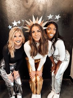 three women posing for the camera in front of a wall with stars and tinsel on it