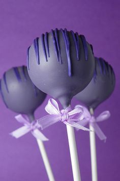 three chocolate lollipops with purple icing on top, tied in a bow