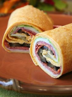 there is a sandwich cut in half on a brown plate with green and yellow cloth