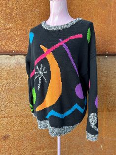 Classic 1980s Esprit Sport cotton crew neck oversized sweater features bright graphic shapes of circles, moon, starburst, squiggles and music notes on a rich black ground. The crew neck, cuffs, and rib hem are in a black and white marled yarn. Easy to wear oversized style. Very good vintage condition, no signs of wear, holes or fading. Measurements are taken with garment flat in inches Bust pit to pit relaxed 46 Waist edge to edge relaxed 39 Shoulder seam to Shoulder seam 25 Sleeve Length - Shou Trendy Multicolor Sweater With Graphic Print, Oversized Retro Sweater, 90s Style Oversized Black Sweater, Vintage Black Sweater With Graphic Print, 90s Oversized Black Sweater, Oversized Multicolor Retro Sweater, Art Mom Aesthetic, Outfit Reference, Graphic Shapes