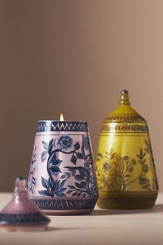 two vases sitting on top of a table next to each other, one with a candle in it