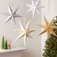 three wooden stars hanging from the ceiling next to a christmas tree