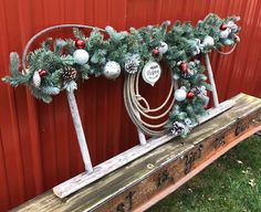 a wooden bench decorated with christmas decorations and pine cones on it's sides, sitting in front of a red wall