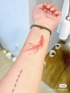 a woman's arm with a red fish tattoo on it