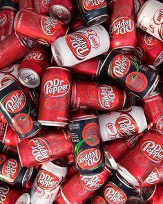 a pile of red and white soda cans sitting next to each other on top of each other