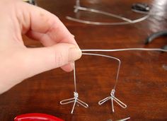 a person is holding wire in front of some scissors on a wooden table with other items