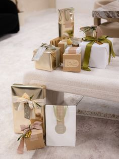 several gift boxes with ribbons and bows on a bench in a living room, all wrapped in gold paper