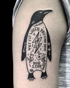 a black and white penguin tattoo on the right thigh, with words written below it