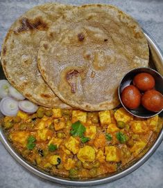 two flat breads and some vegetables on a metal plate with a bowl of red onions