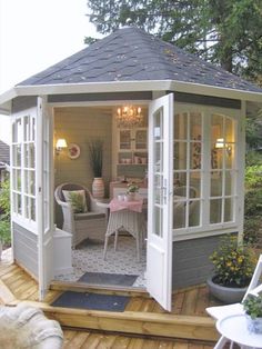 a gazebo sitting on top of a wooden deck next to a table and chairs