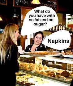 a woman standing in front of a bakery counter talking to another woman about what she wants