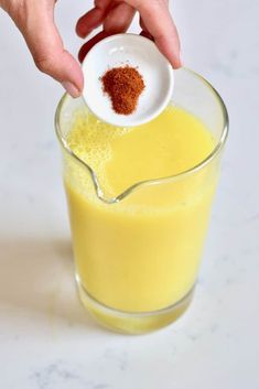 someone is adding spices to a glass of orange juice