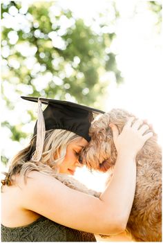 a woman in a graduation cap hugging her dog