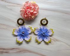 Bloom with boho beauty in these purple & gold Flower Seed Bead Stud Earrings! 🌹✨  Handmade with intricate petals, these earrings bring a touch of floral elegance to your style. Perfect for everyday wear, these stud earrings add a pop of color to any look. Embrace the handmade charm and let your ears blossom with this vibrant accessory. 🌺 🌟DETAILS🌟 🔹Free shipping UK 🔹Made with quality 11/0 czech beads 🔹Made using nylon weaving thread 🔷Length: approx. 2.3 inches 🔷Stainless Steel studs. 🔔There may be some color differences due to monitor, light or phone settings.  💎More jewellery for yourself or loved ones found here 👇 https://www.etsy.com/uk/shop/MadalinaJewelry 🔆Follow me on instagram for updates @madalinajewelry If you have any questions, please feel free to message me and I w Purple Flower Bohemian Earrings, Bohemian Purple Flower Earrings, Bohemian Gold Flower Earrings Handmade, Purple Flower Shaped Beaded Earrings For Gifts, Seed Bead Stud Earrings, Flower Seed Bead, Bead Stud Earrings, Handwoven Earrings, Boho Beauty