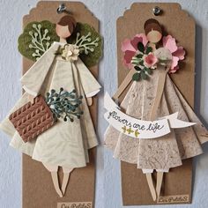 two tags with paper angels on them hanging from the wall next to eachother