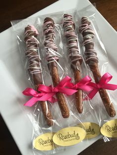 chocolate covered donuts wrapped in pink ribbon on a white platter with name tags