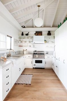 the kitchen is clean and ready for us to use it's white cabinets, wood flooring, and overhead lighting