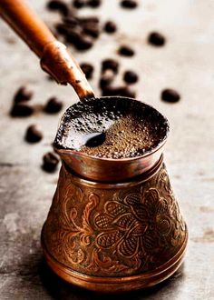 a metal cup filled with coffee beans and a wooden spoon sticking out of the top