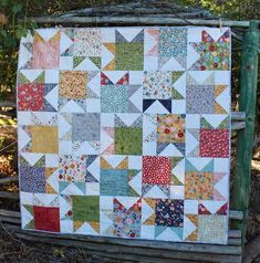 a patchwork quilt is hanging on a fence