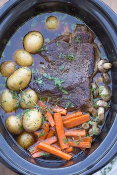 pot roast with carrots, potatoes and parsley in a crock pot on a wooden table